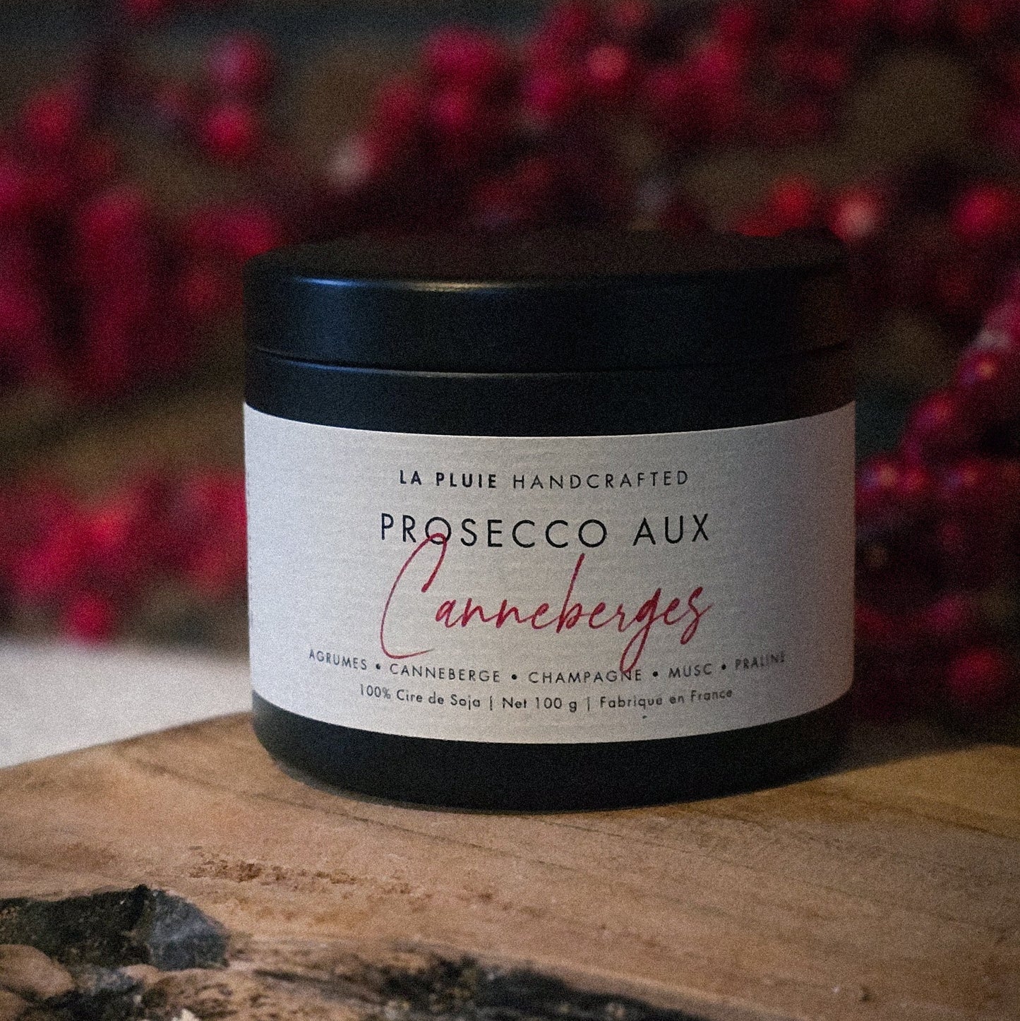 Jar of Prosecco aux canneberges on a wooden surface with red berries in the background