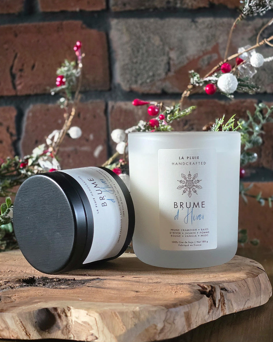 Candle and container on a wooden surface with a brick wall background