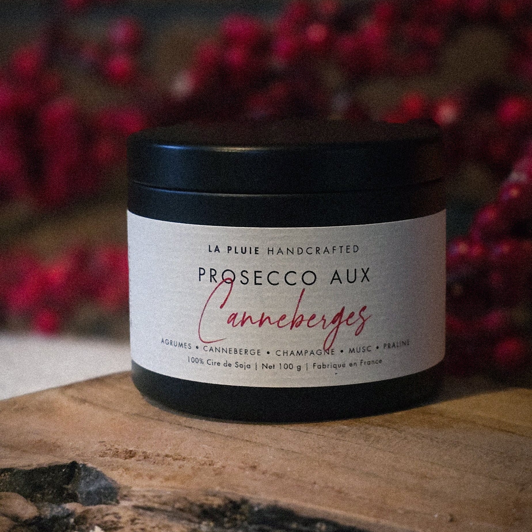Jar of Prosecco aux canneberges on a wooden surface with red berries in the background
