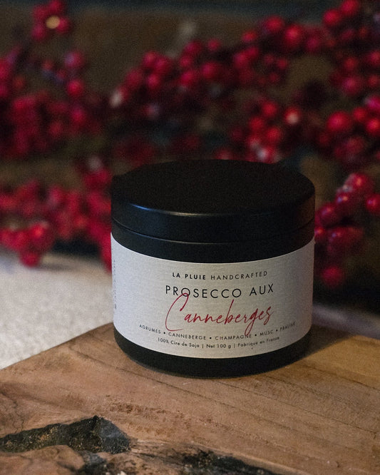 Jar of Prosecco Aux canneberges on a wooden surface with red berries in the background