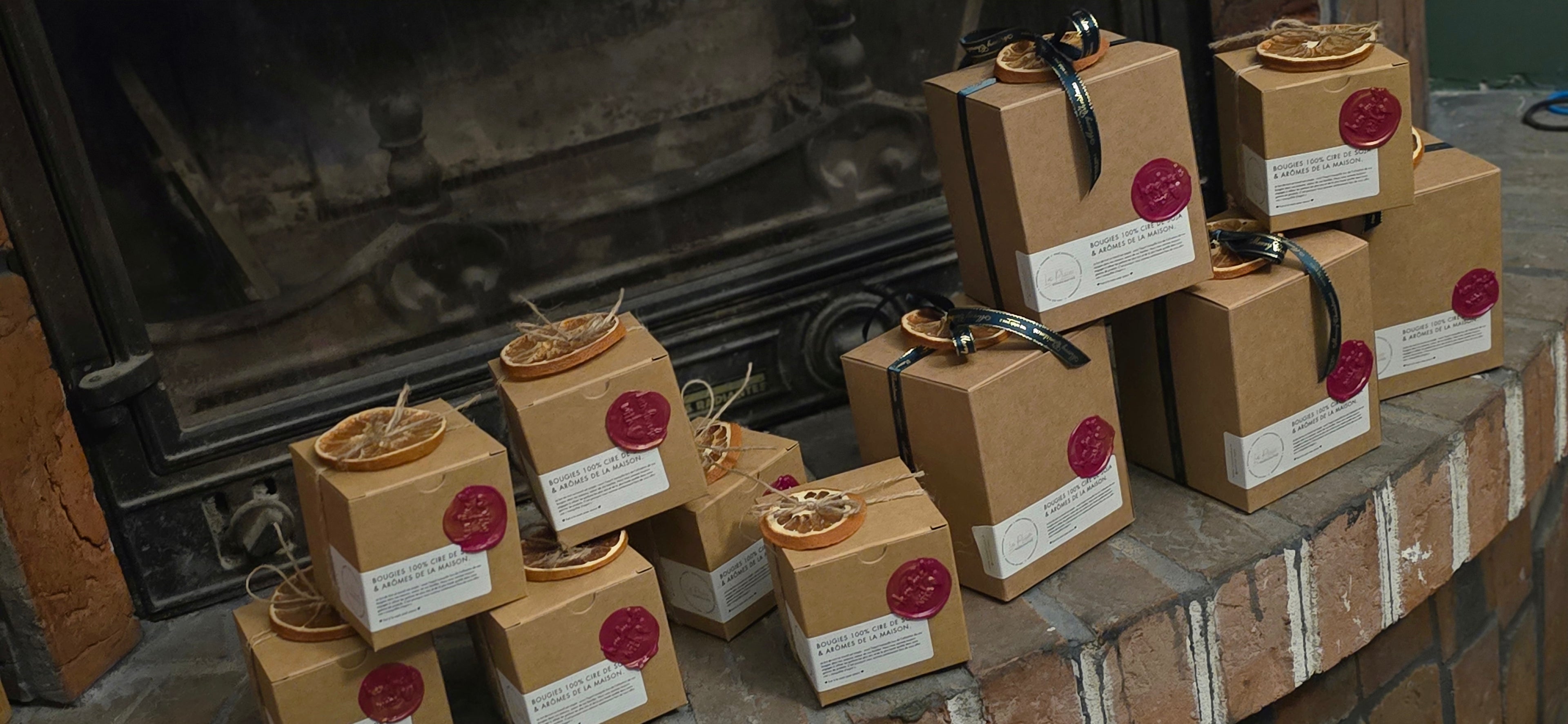 Row of brown gift boxes with red labels on a stone surface in front of a fireplace.